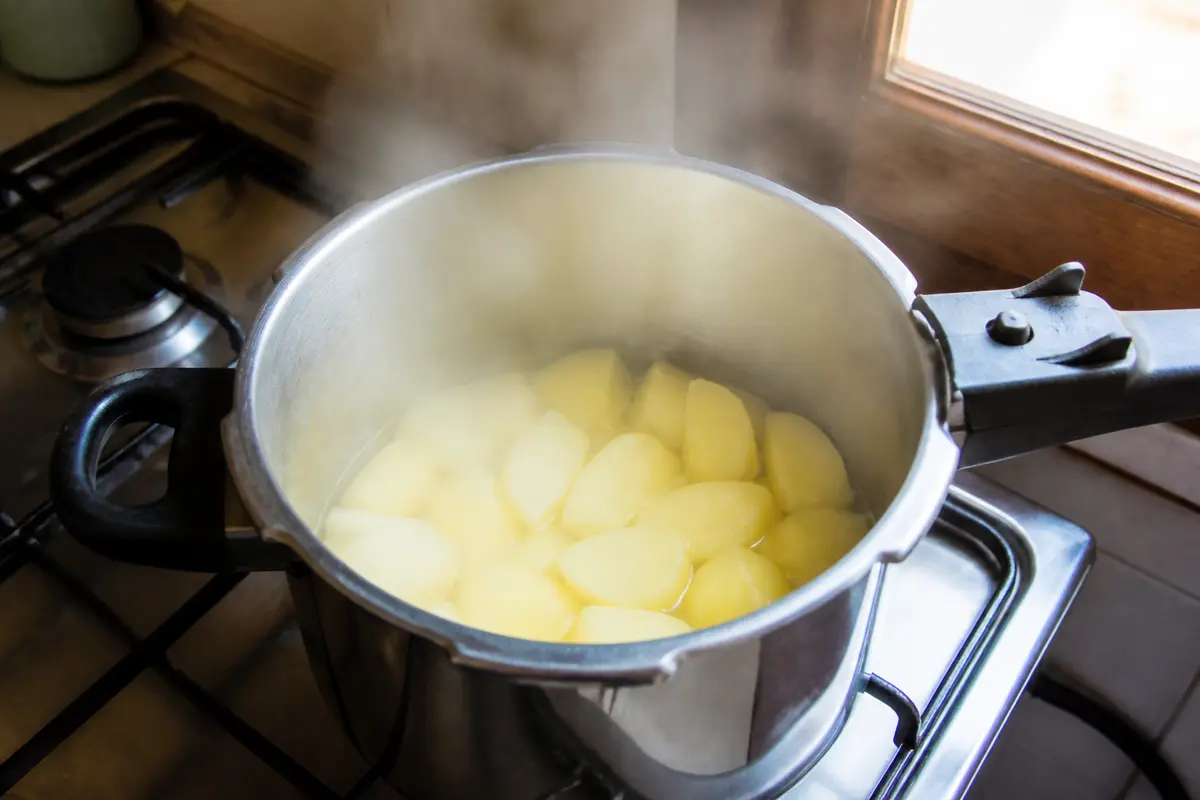 Pommes de terre en cuisson à la cocotte-minute sur une gazinière en cuisine.